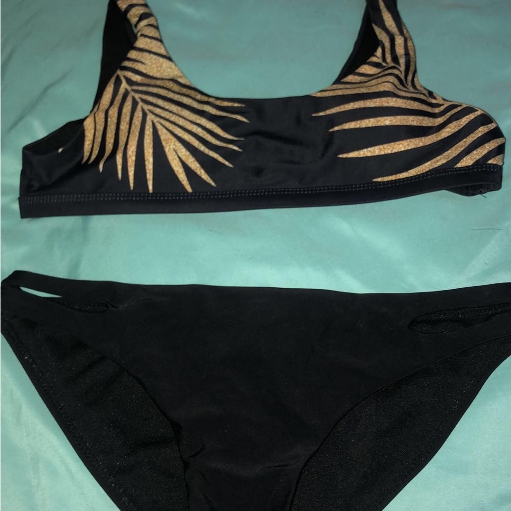 It is a black bathing suit with gold designs on the top
